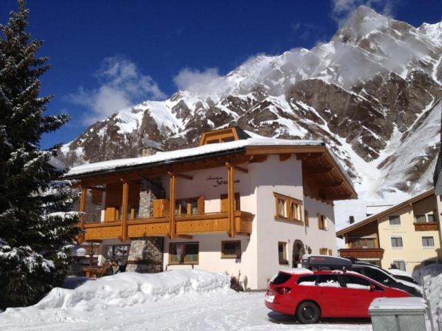 eine Ski-Lodge mit einem vor ihr geparkt roten Auto in der Unterkunft Chasa Seraina in Samnaun