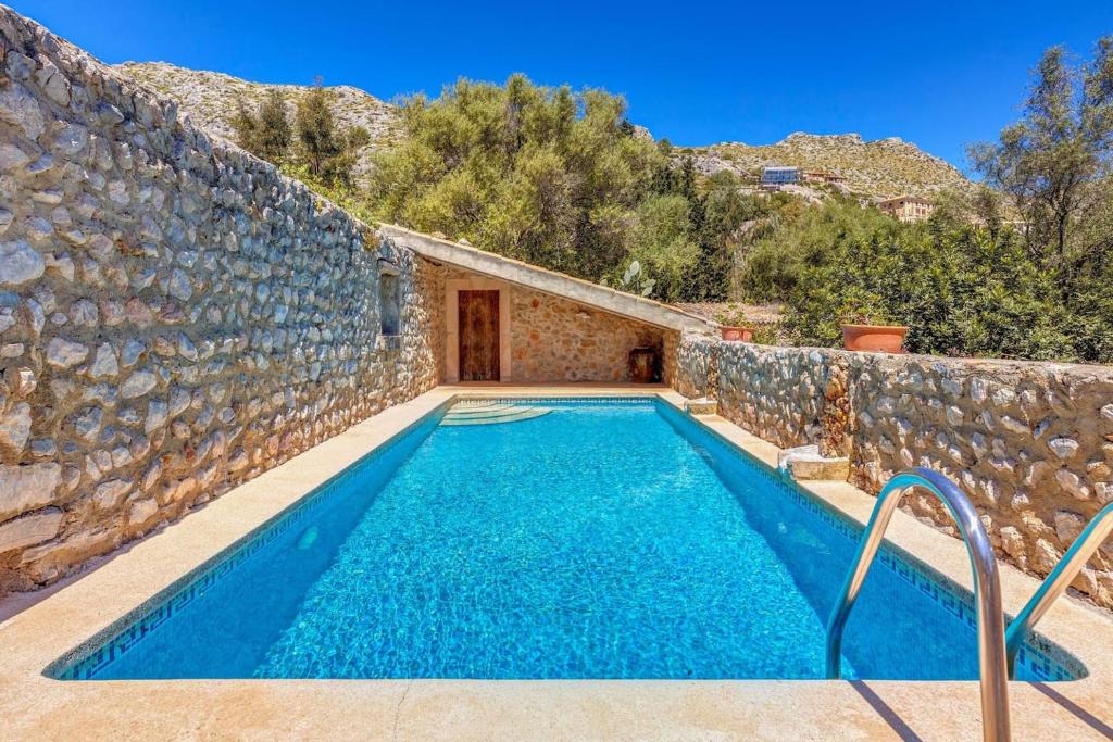 a swimming pool in a stone building with a stone wall at La font in Pollença