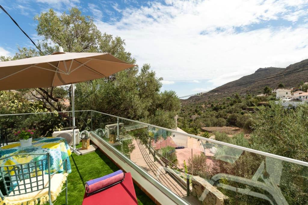 a balcony with an umbrella and chairs on the grass at Charming House in Temisas with Parking and Air Conditioning in Temisas