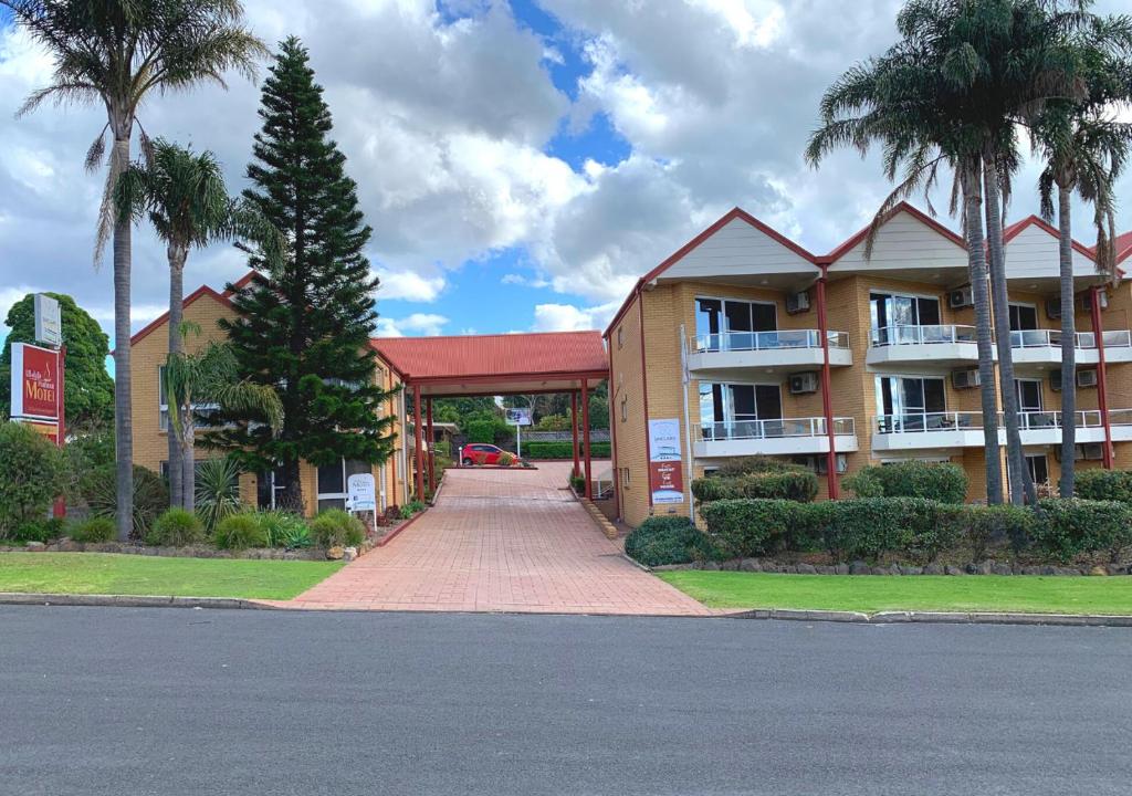 a large apartment building with palm trees and a driveway at Ulladulla Harbour Motel in Ulladulla