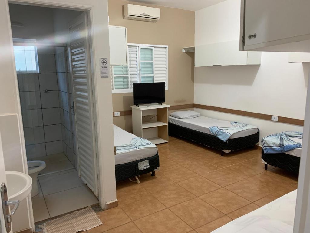 una piccola camera con due letti e un bagno di Hotel 7 a Três Lagoas