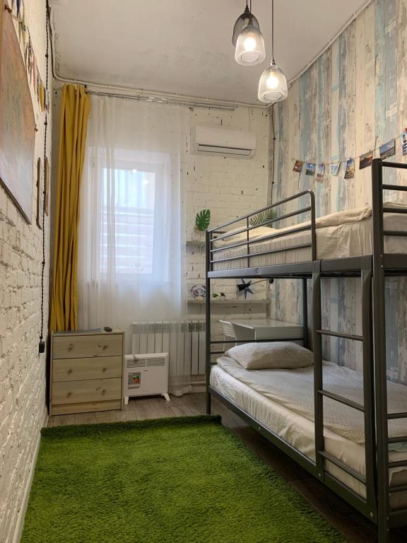 ウラジオストクにあるネプチュネア アパートメンツのベッドルーム1室(二段ベッド2台、緑のラグ付)