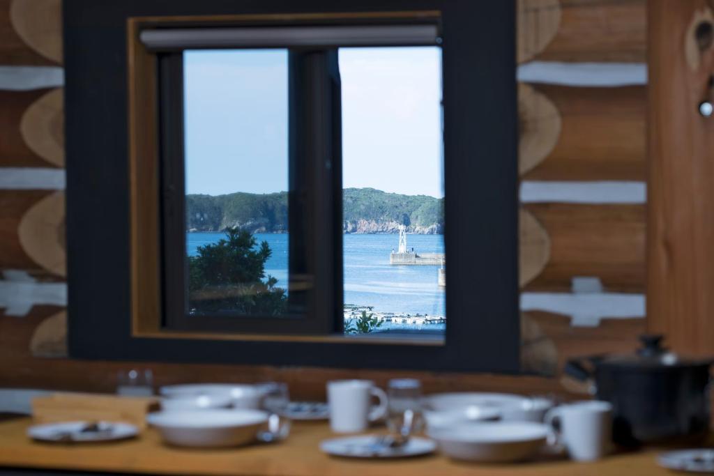 una mesa con una ventana con vistas al agua en LOG HOUSE at Shima en Shima