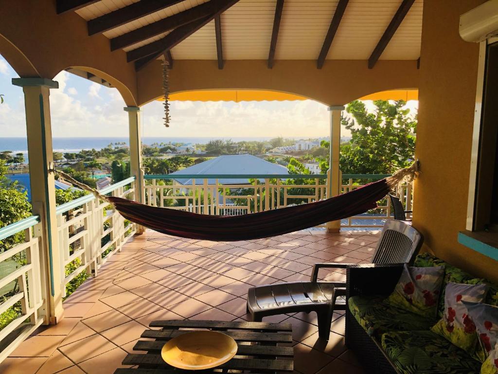 a hammock on a porch with a view of the ocean at Appartement spacieux à Saint-François 150 m² avec piscine partagée ! in Saint-François