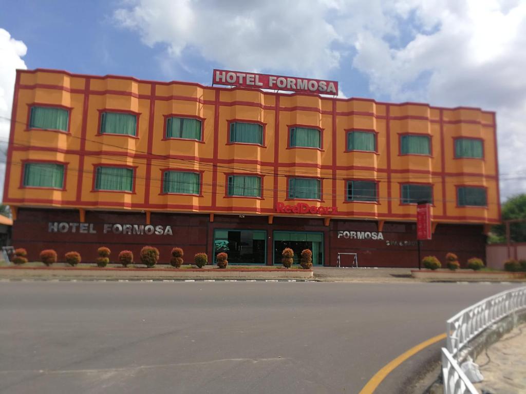 an orange building with a hotel on top of it at Hotel Formosa Jambi in Paalmerah