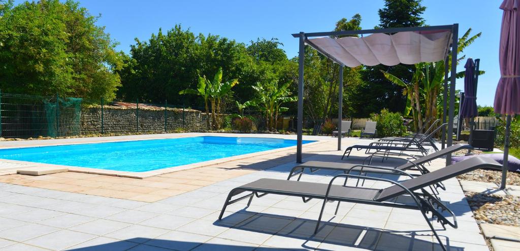 a pool with chairs and a table and a umbrella at Gites Jardin-darcy - Piscine au sel in Bois