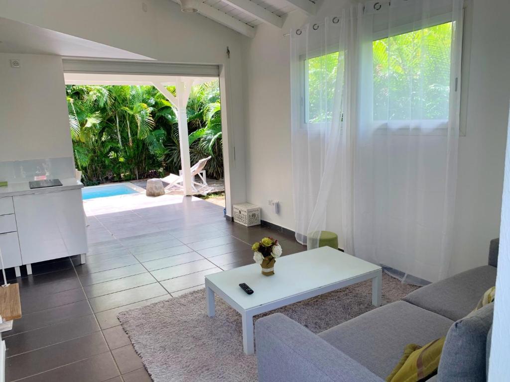 a living room with a couch and a table at Appartement confortable au Moule 60 m² avec piscine privée in Le Moule