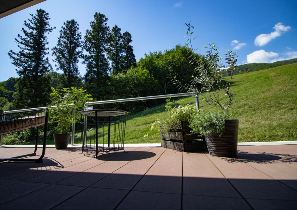 eine Terrasse mit einer Bank und einem Tisch mit Pflanzen in der Unterkunft STARRY in Hakuba