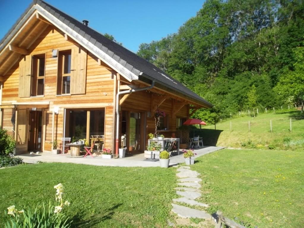 ein Blockhaus mit einem Rasenplatz davor in der Unterkunft La Buissonnière in Le Noyer