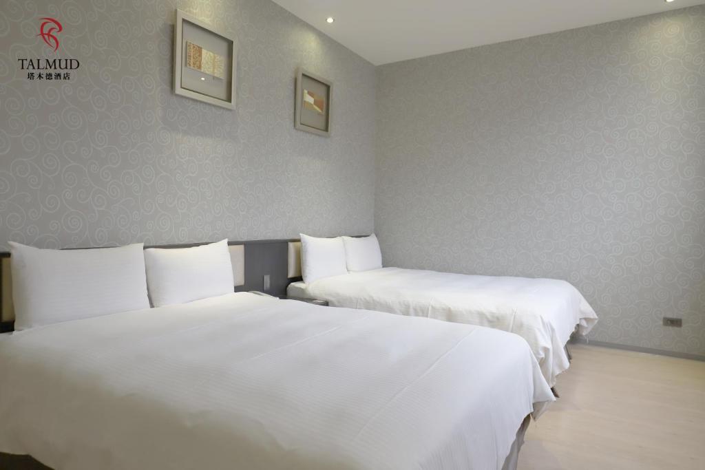 two beds in a hotel room with white sheets at Talmud Hotel Taichung in Taichung