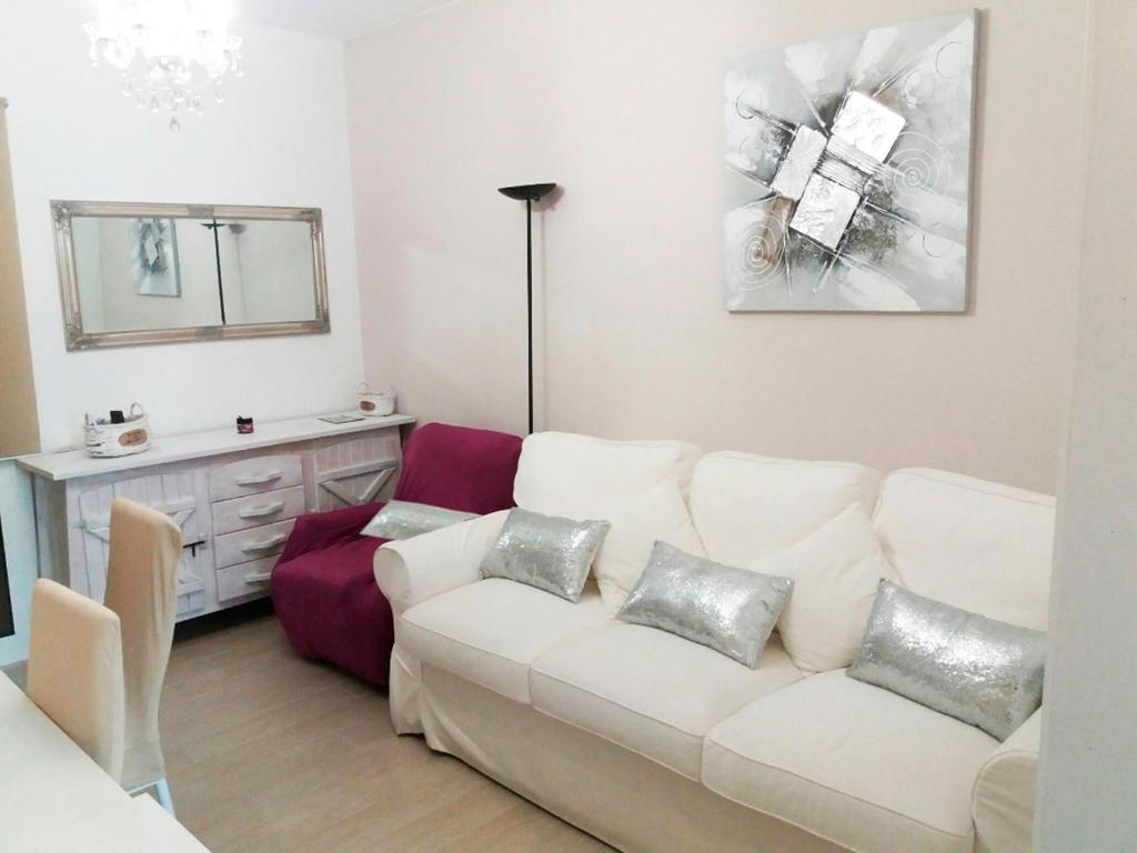een woonkamer met een witte bank en een spiegel bij Apartamentos Lorena 1A in Segur de Calafell