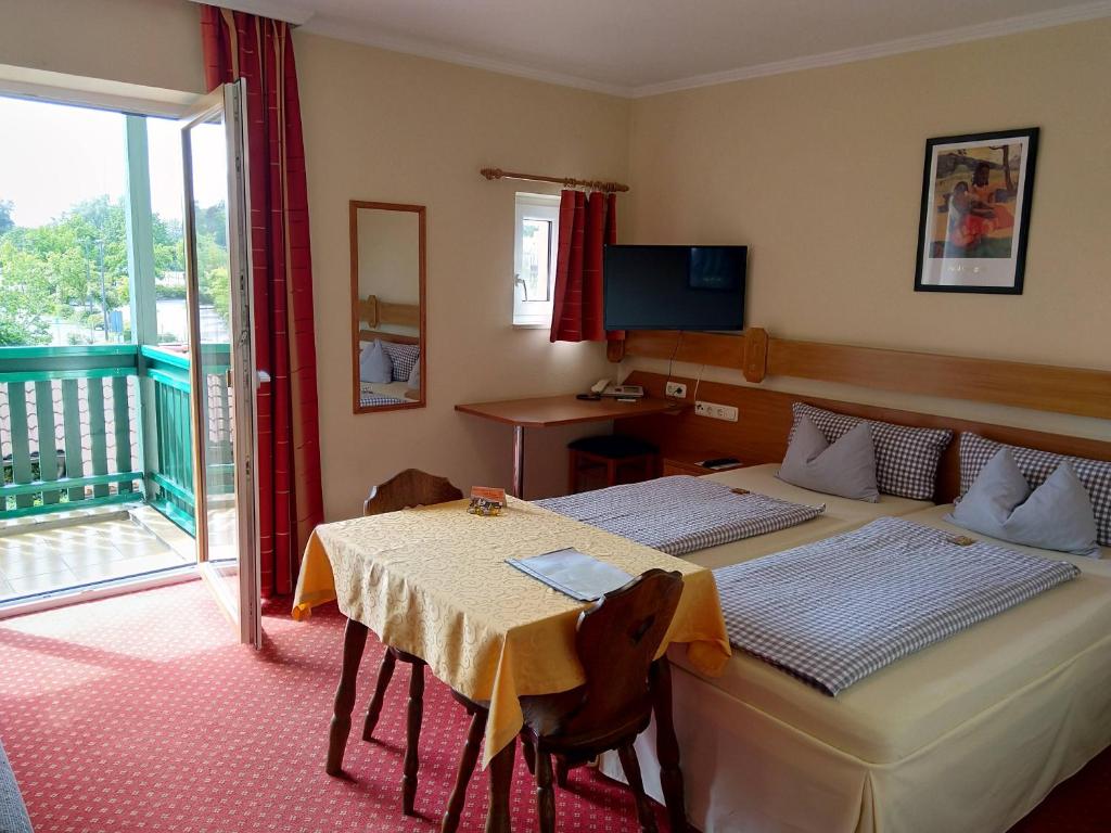 um quarto com 2 camas, uma mesa e uma varanda em Hotel Fortuna em Bad Gögging