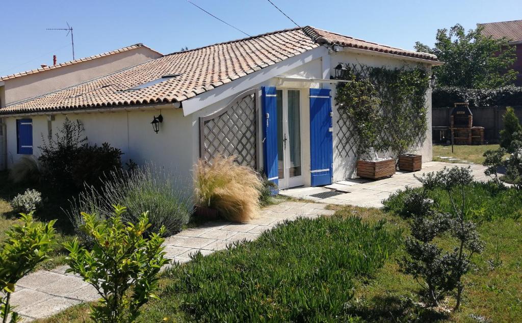 une petite maison blanche avec des portes bleues dans l'établissement Gîte Domangé-Audenge, à Audenge