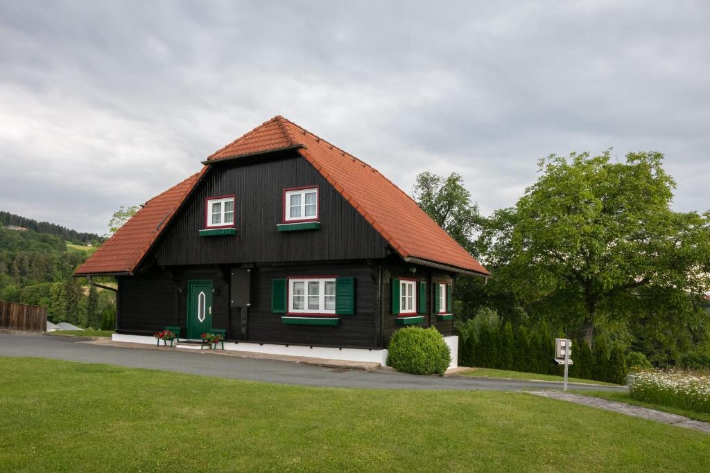 uma casa preta com um telhado vermelho em Ferienhaus Stoiser em Sankt Stefan ob Stainz