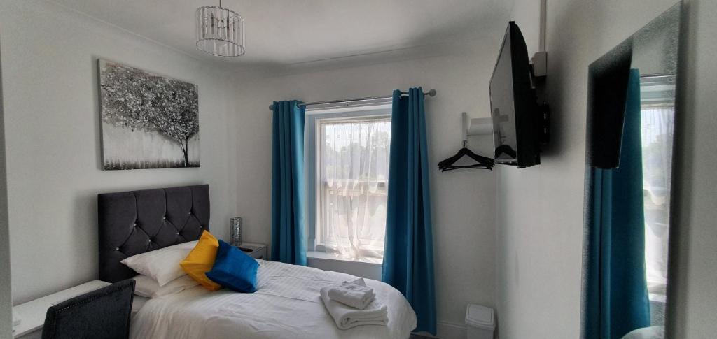 a bedroom with a bed with blue curtains and a window at Holly Lodge in Weston-super-Mare