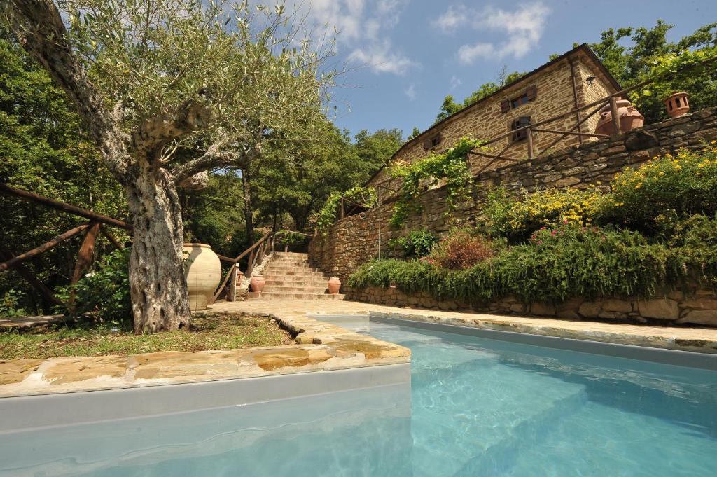 a swimming pool with a tree next to a building at Casale Grillo in Cortona