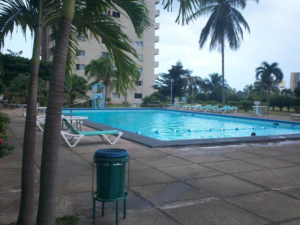 una piscina con palmeras y un cubo de basura en Turtle Towers, en Ocho Ríos