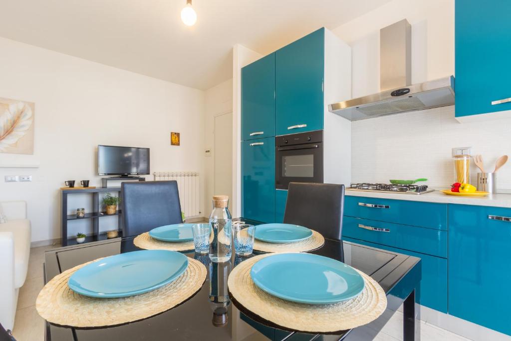a kitchen with blue cabinets and a table with blue plates at Appartamento Calipso - MyHo Casa in Tortoreto Lido