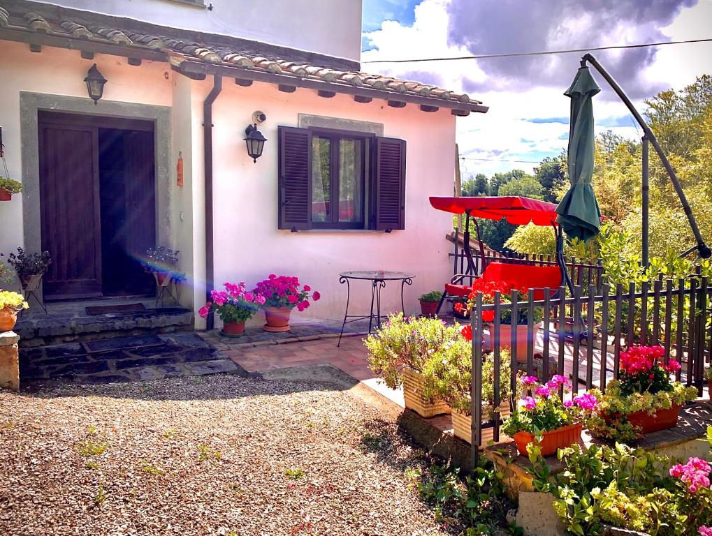 ein rosafarbenes Haus mit Blumen, einem Tisch und einem Regenschirm in der Unterkunft Antico Fienile in Celleno