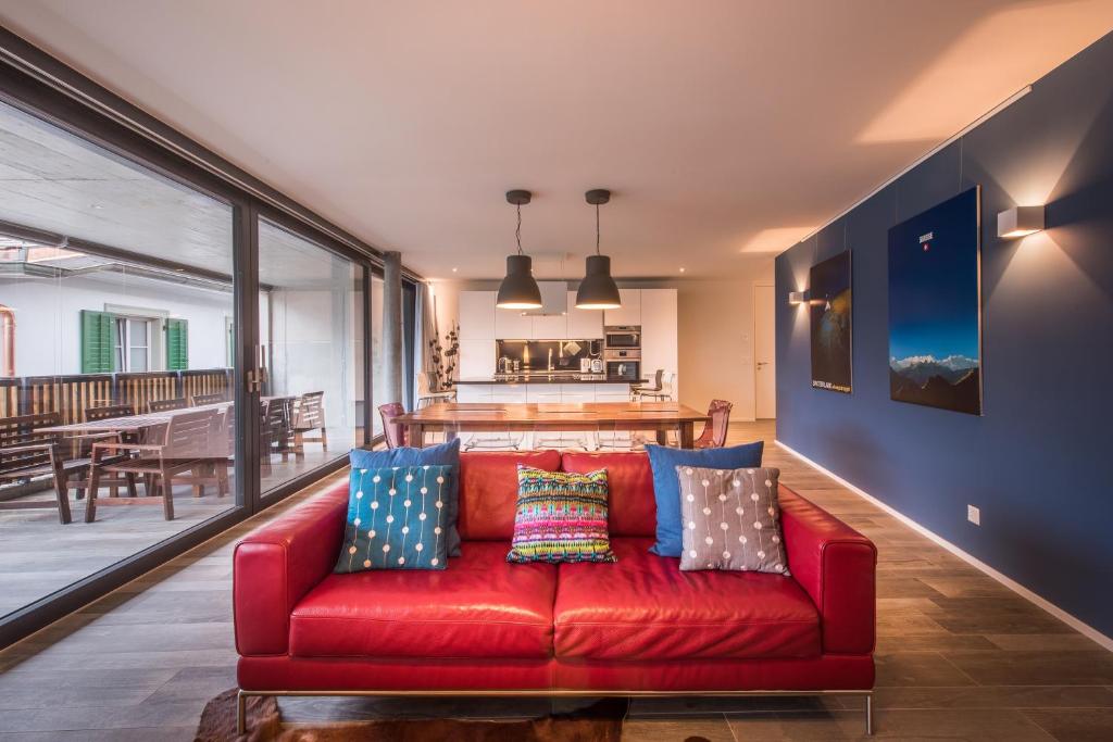 un sofá rojo con almohadas en la sala de estar en Independance Penthouse en Interlaken