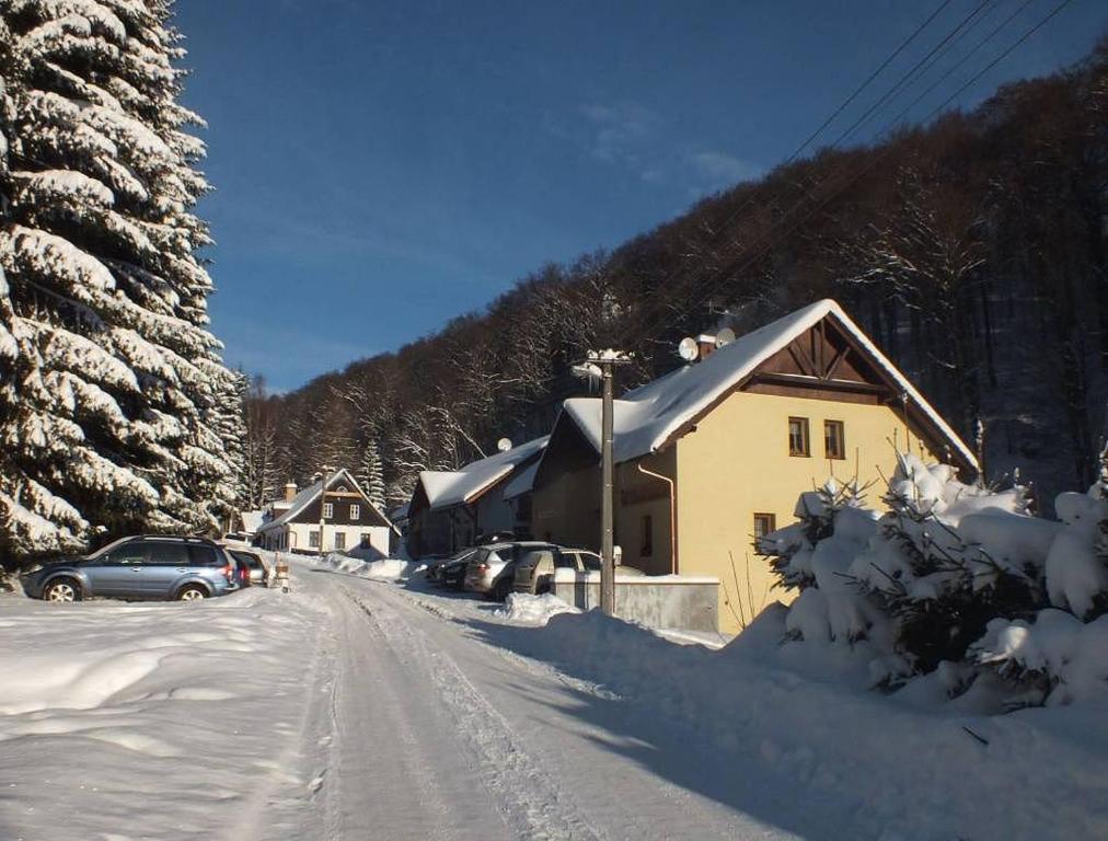 a snow covered street with a house and a car at Penzion nad Sněžným potokem in Žacléř
