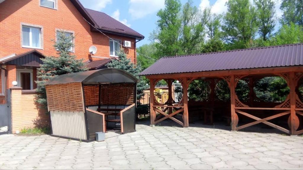 a gazebo with a grill next to a house at Золотой Берег in Poltava