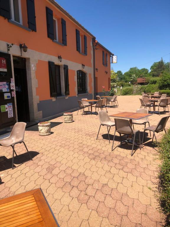 un patio avec des tables et des chaises en face d'un bâtiment dans l'établissement Hôtel Restaurant La Manse, à Dornecy