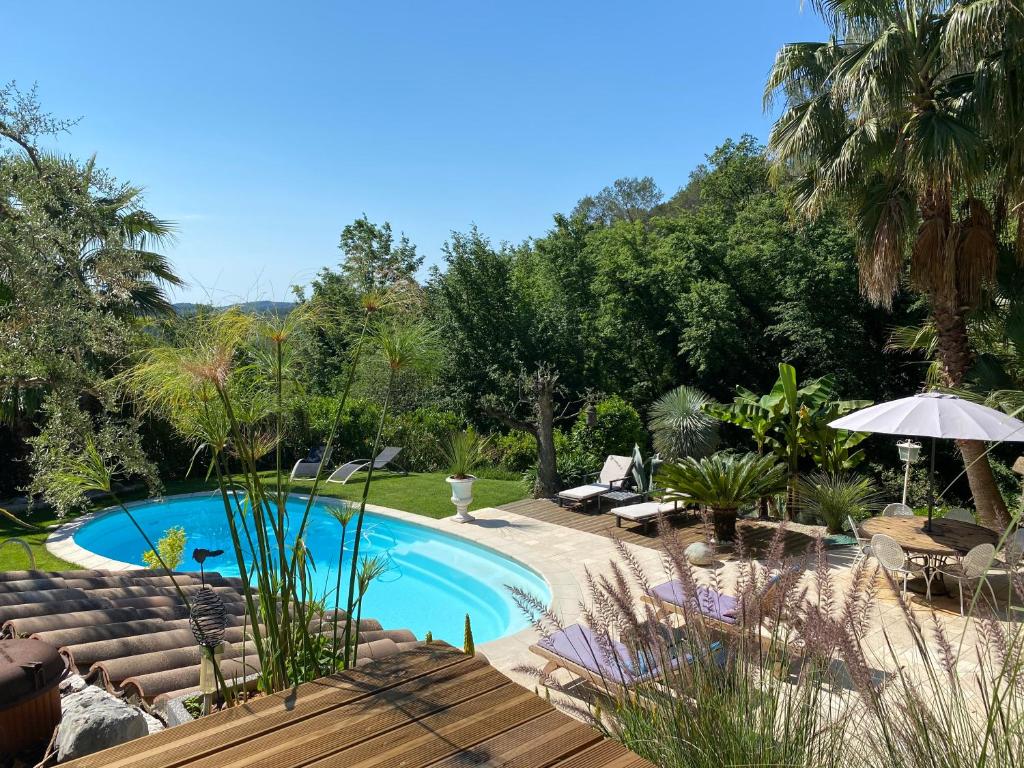 a pool with chairs and an umbrella in a yard at Le Maskalou in La Colle-sur-Loup