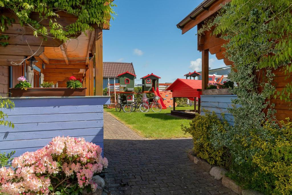 una casa con una valla y flores en un patio en Domki Rekin, en Rewal