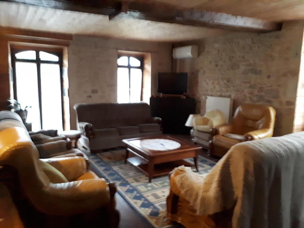 ein Wohnzimmer mit Sofas und einem TV in der Unterkunft Grand gîte à la campagne in Missé