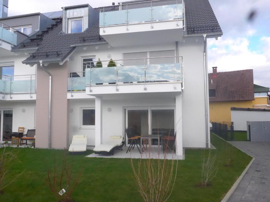 a white house with a balcony and a table at Ferienwohnung am Yachthafen in Kressbronn am Bodensee