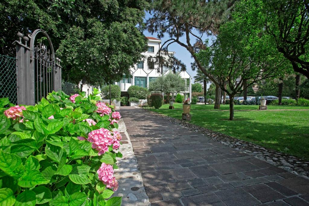 una pasarela frente a una casa con flores rosas en Park Hotel Ai Pini & Restaurant Ai Pini, en Mestre