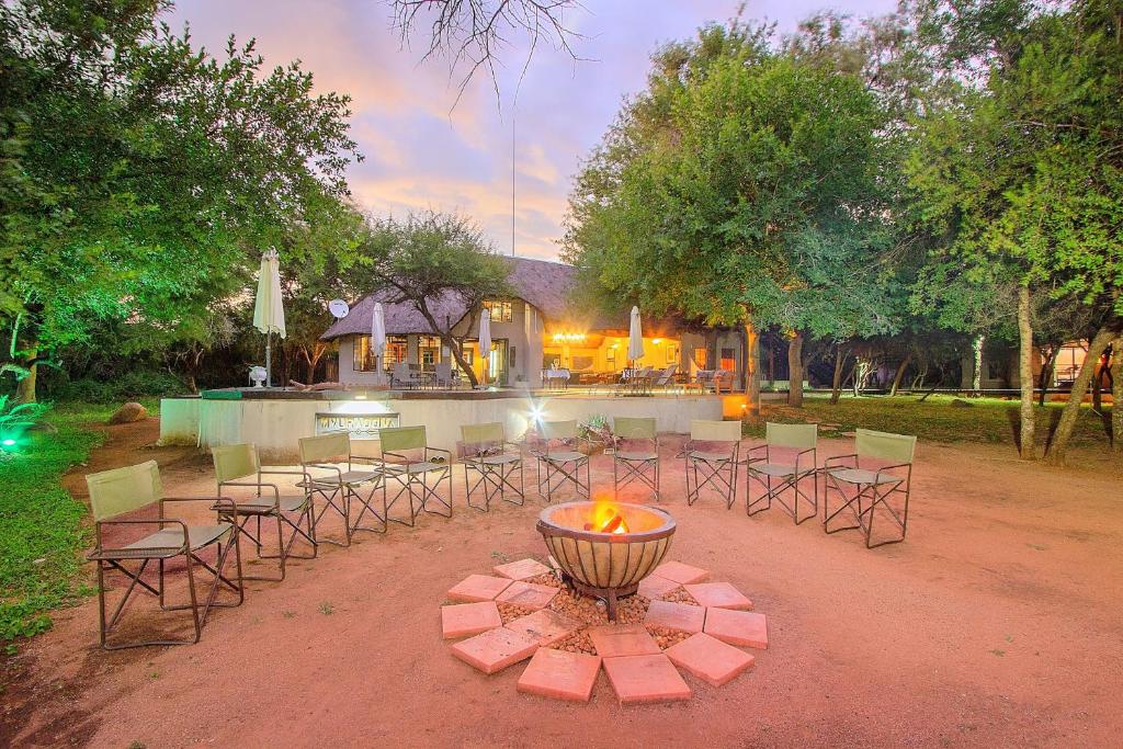 a group of tables and chairs with a fire pit at Mvuradona Safari Lodge in Marloth Park