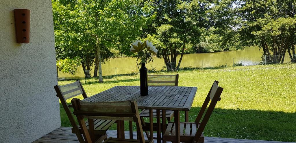 una mesa de madera con un jarrón con una flor. en COTTAGE privé avec TERRASSE et PISCINE - bord de LAC & FORÊT, en Miramont-de-Guyenne