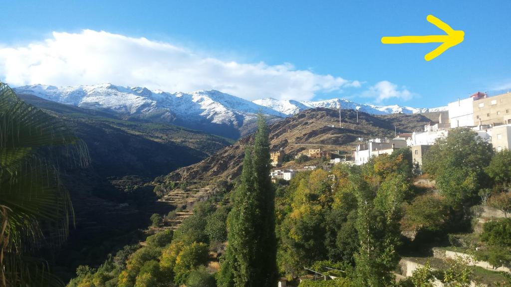 un avión volando sobre una montaña con montañas cubiertas de nieve en La flecha hostel, en Abrucena