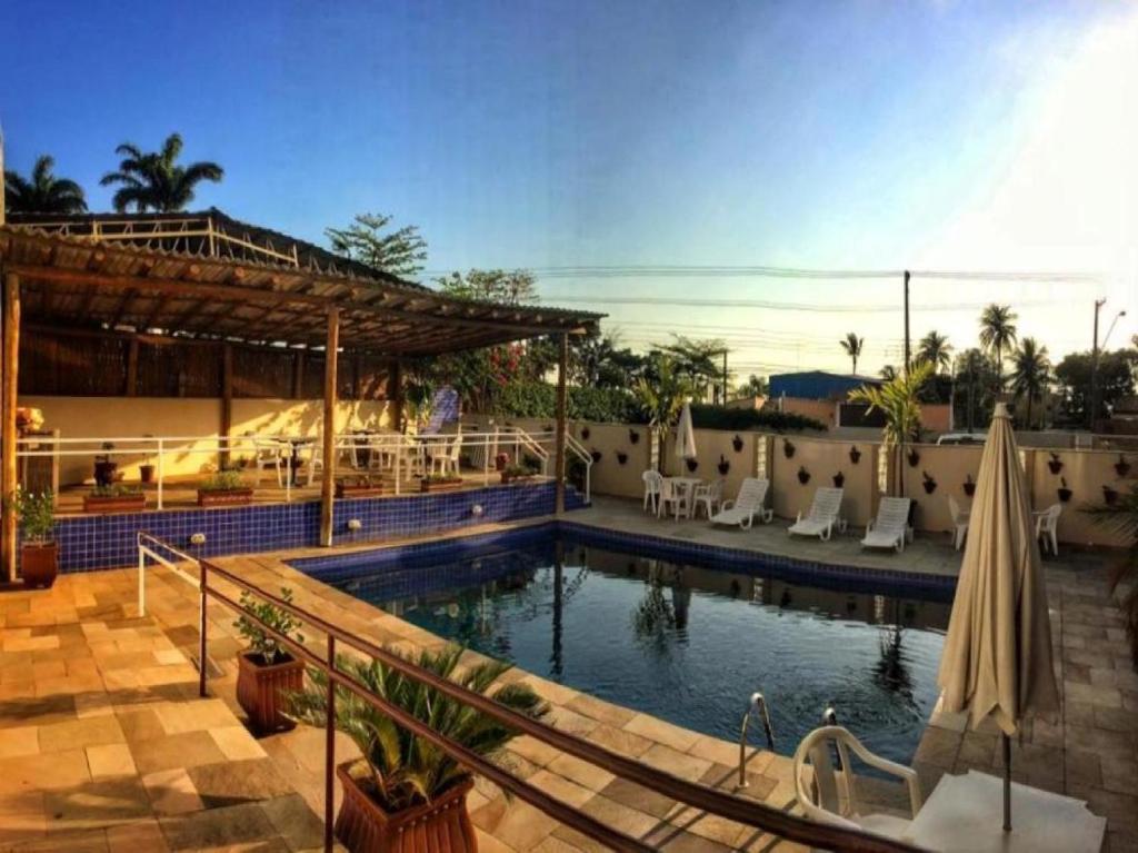ein Pool mit Sonnenschirmen und Stühlen in einem Resort in der Unterkunft Hotel do Sol Executive in São Sebastião