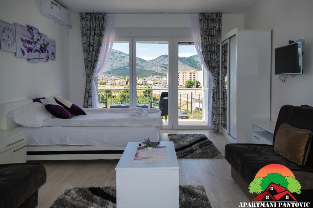 a living room with a bed and a large window at Apartmani Pantovic - Apartman 2 in Trebinje