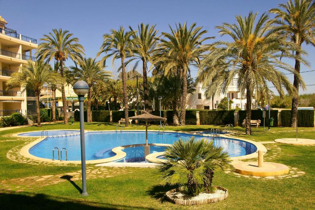 ein Swimmingpool in einem Resort mit Palmen in der Unterkunft Apartamento en Sueños de Denia III muy cerca de la playa y del pueblo in Denia