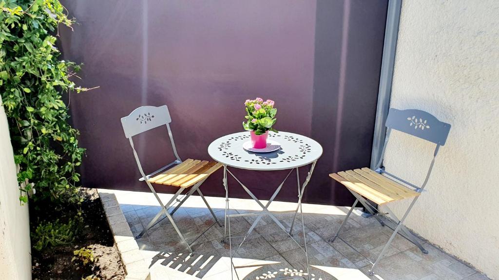 una mesa con dos sillas y un jarrón de flores en "LE TRAMWAY" Appartement 150m gare des Aubrais, en Fleury-les-Aubrais