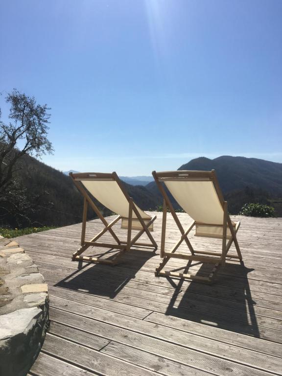 two chairs sitting on a deck with mountains in the background at Encanto Di Arlia in Fivizzano