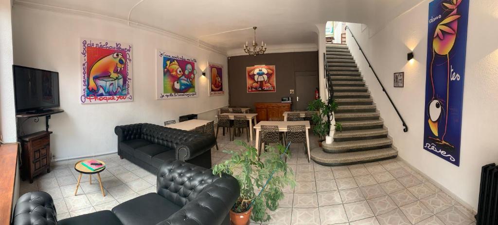 a living room with black leather furniture and a staircase at Hotel Le Centre in Le Boulou