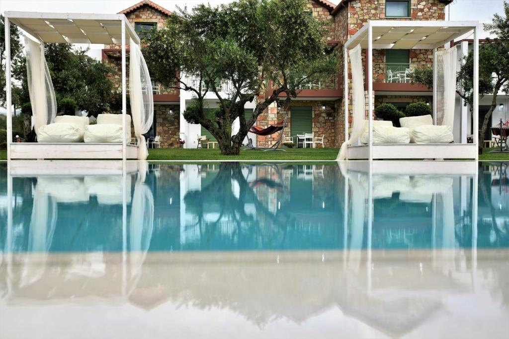 uma piscina com cadeiras brancas e uma casa em Messinian Horizons em Marathópolis
