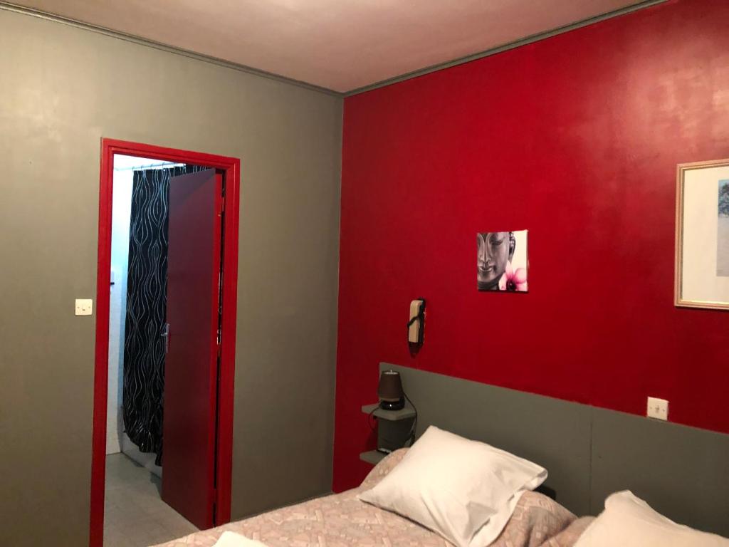 Un dormitorio con una pared roja y una cama en La Trinite en Saint Firmin