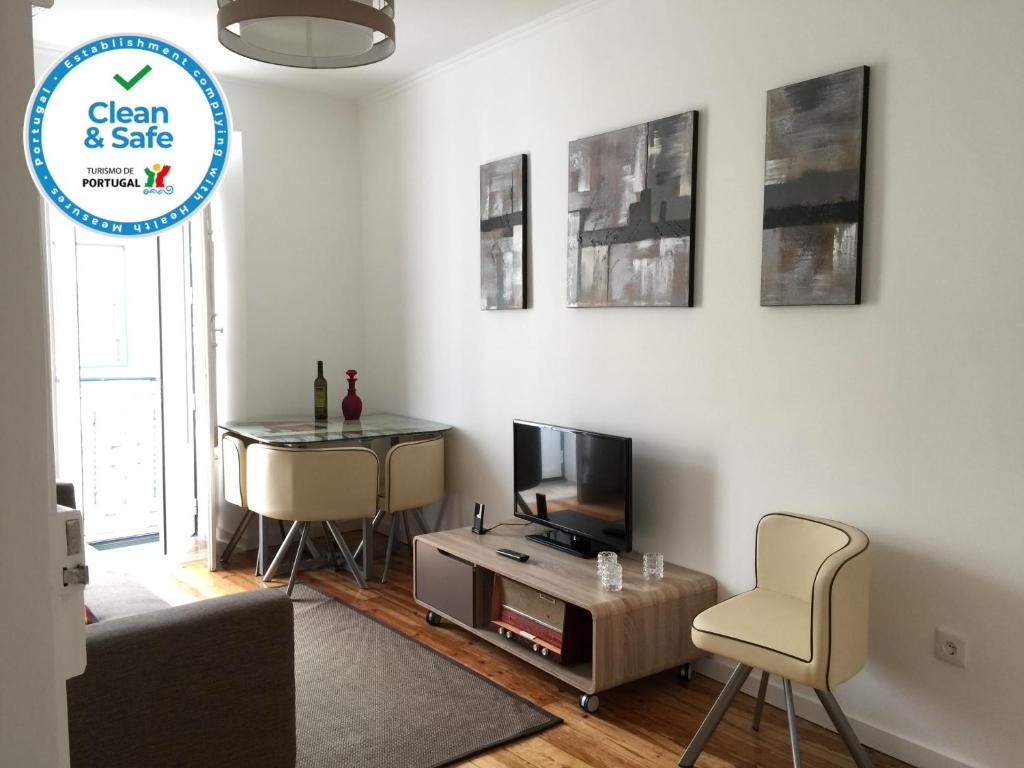 ein Wohnzimmer mit einem TV, einem Stuhl und einem Tisch in der Unterkunft Bairro Alto Studios & Flats by Lisbon Village Apartments in Lissabon