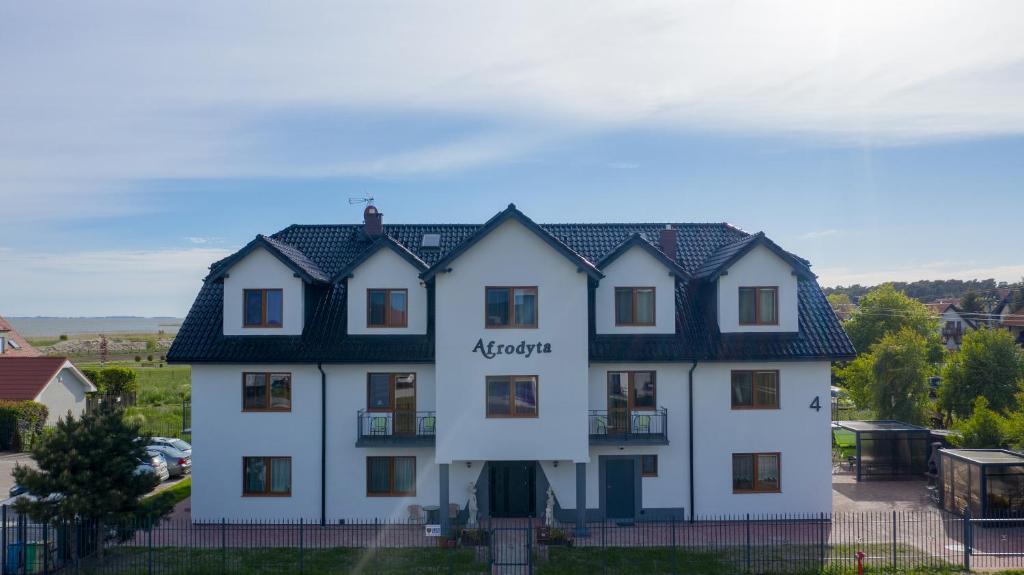 una casa blanca con techo negro en Willa Afrodyta, en Krynica Morska