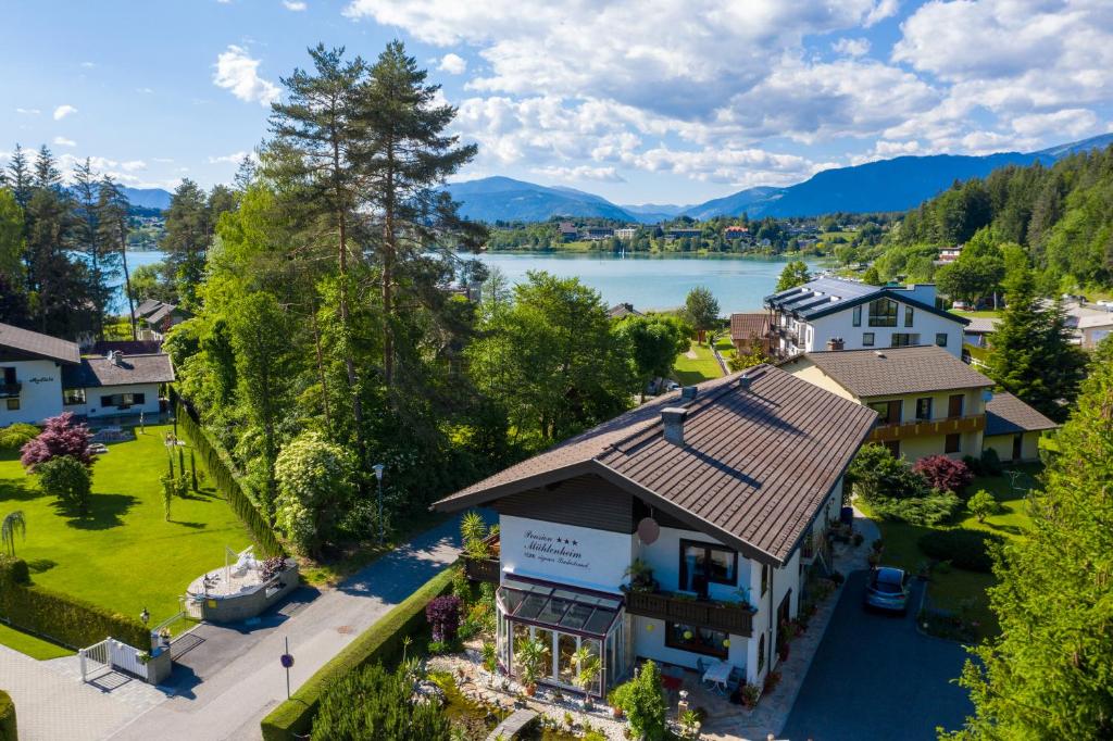 eine Luftansicht eines Hauses mit See in der Unterkunft Pension Mühlenheim in Egg am Faaker See