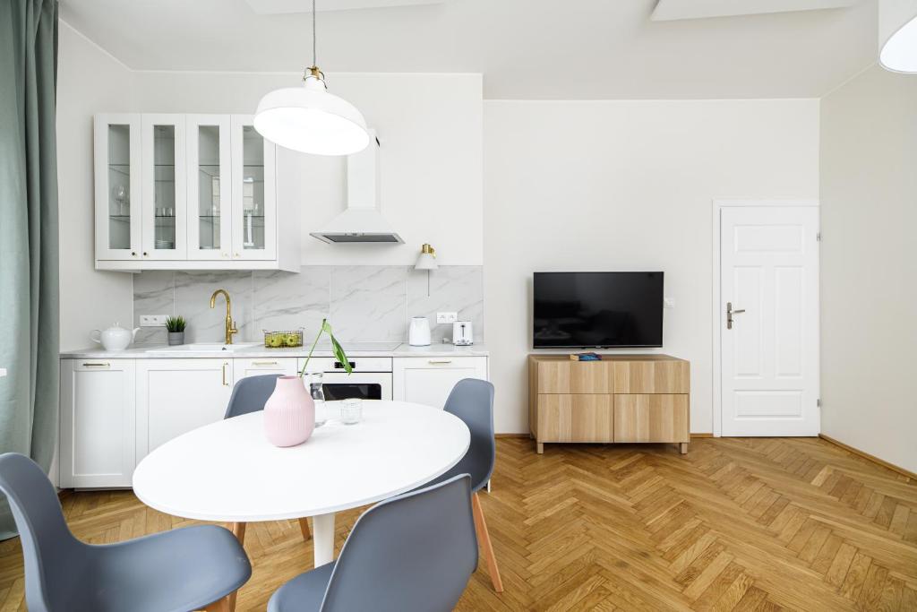 een keuken en eetkamer met een witte tafel en stoelen bij Native Apartments Żuławskiego 8 in Krakau