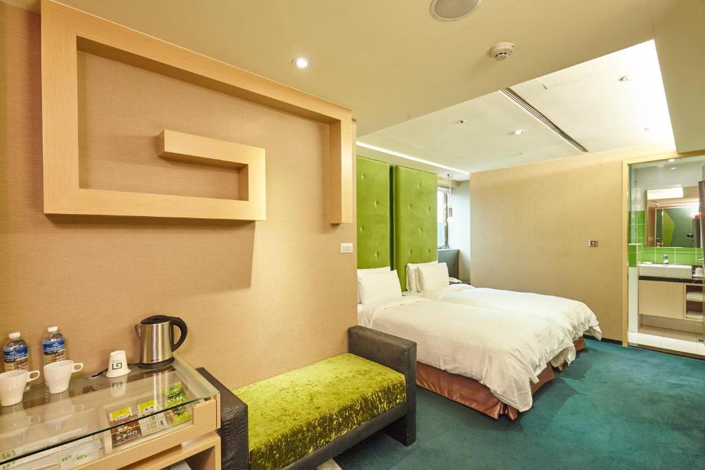 台北的住宿－台北集賢商旅，一间卧室设有一张大床和一张黄色长凳