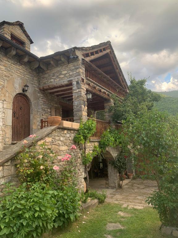 Casa de piedra con porche y puerta de madera en Casa Alejandra, en Fiscal