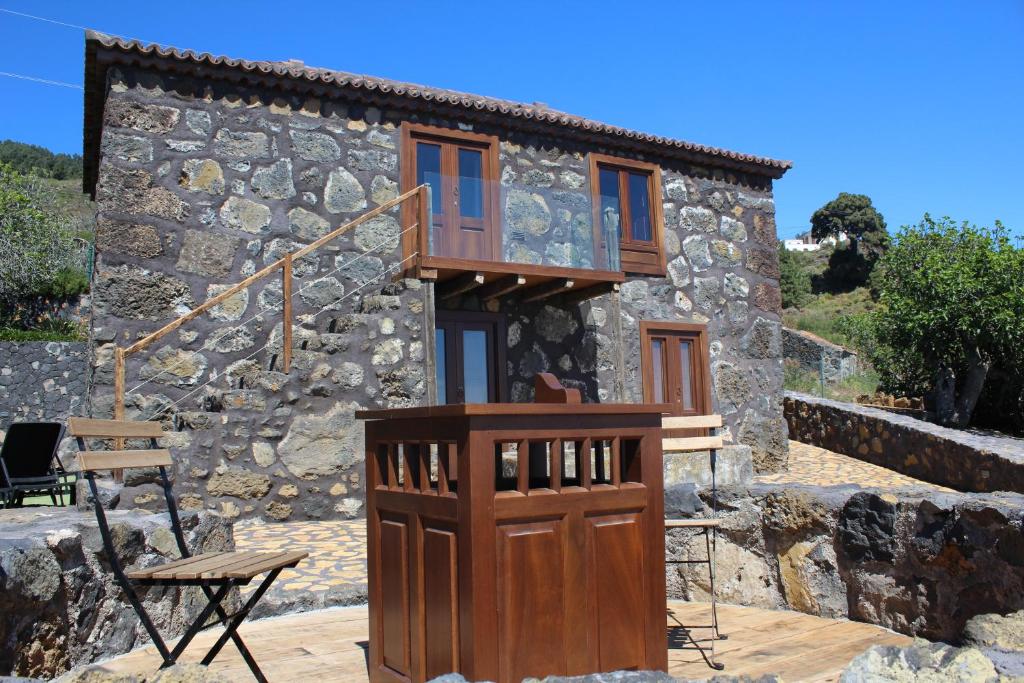 una casa de piedra con una puerta de madera delante de ella en Casa Rural Quinta Los Naranjos en Tigalate